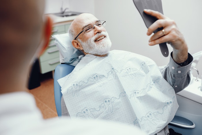 Smiling patient looking at teeth with a hand mirror