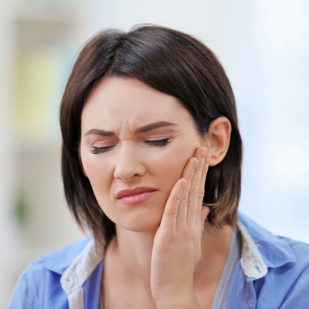 woman holding her jaw in pain
