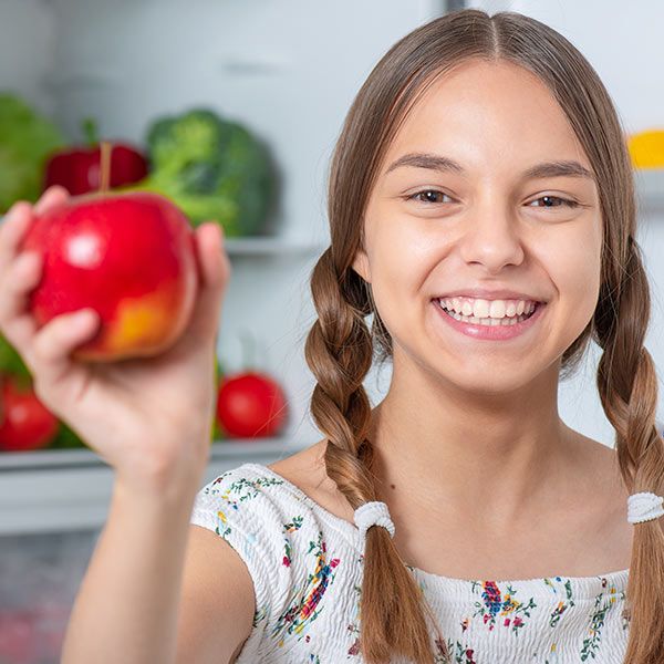 Young girl with braids holding up apple